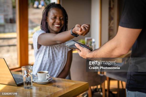 african american woman paying with smart watch for coffee in restaurant. woman in restaurant making contactless payment - watch payment stock pictures, royalty-free photos & images