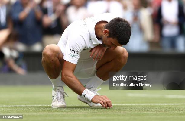 Novak Djokovic of Serbia celebrates winning his men's Singles Final match against Matteo Berrettini of Italy by picking grass from the court on Day...