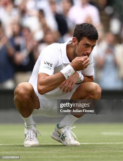 Novak Djokovic of Serbia celebrates winning his men's Singles Final match against Matteo Berrettini of Italy by picking grass from the court on Day...