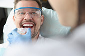 Doctor tries on plastic mouthguard for young smiling man to correct bite