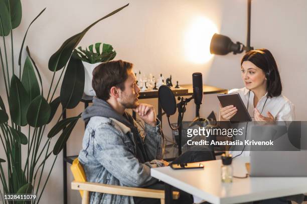 man and woman at a nice home office recording studio working together, creating podcast. - direkt stock-fotos und bilder