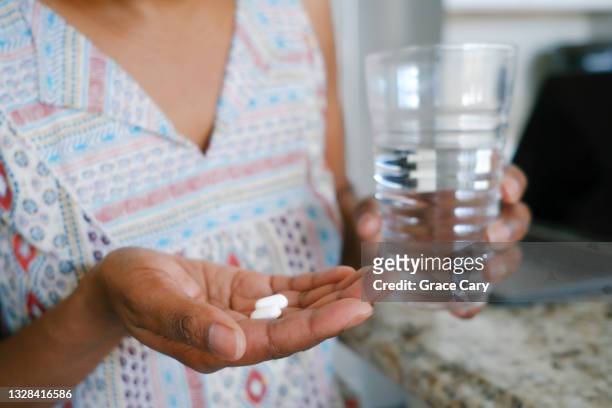 woman holds pills in palm of hand - 止痛劑 個照片及圖片檔