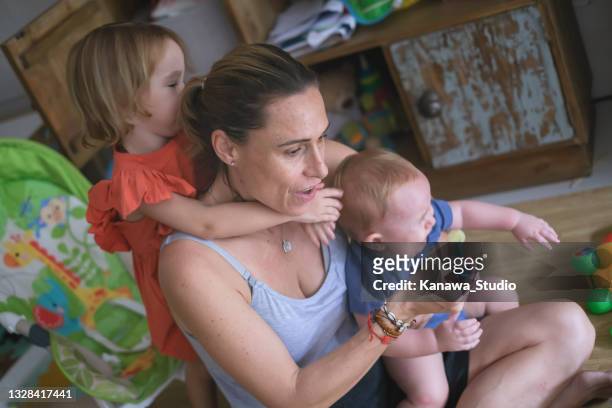 overworked mother caring for kids - busy toddlers stock pictures, royalty-free photos & images