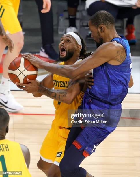 Patty Mills of the Australia Boomers is fouled by Kevin Durant of the United States during an exhibition game at Michelob Ultra Arena ahead of the...