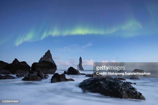 aurora display at reynisfjara black sand beach, vik, south iceland. - dramatic landscape stock pictures, royalty-free photos & images