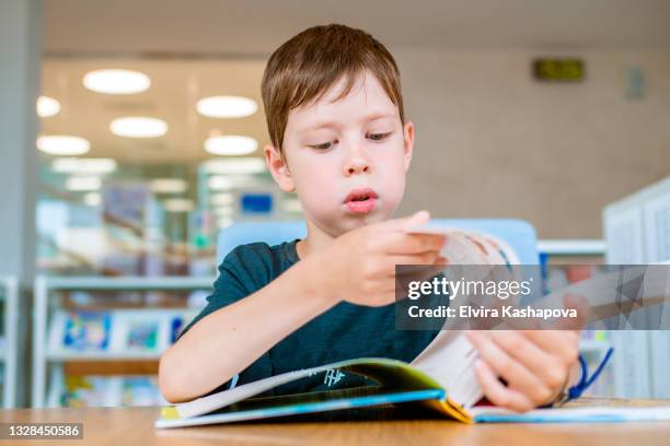 a schoolboy reads a book in the library. distance learning outside of school. - enciclopedia stock pictures, royalty-free photos & images