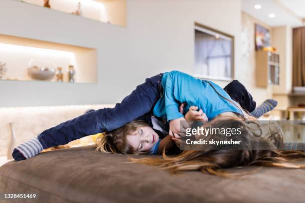 small brothers fighting on sofa at home. - sibling conflict stock pictures, royalty-free photos & images