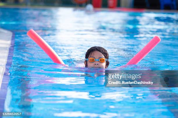 child girl swimming. the pool noodles make learning to swim. - school holiday stock pictures, royalty-free photos & images