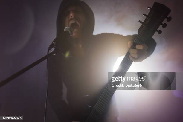 heavy metal rock guitarist playing guitar in a live show with stage lights - rockmuziek stockfoto's en -beelden