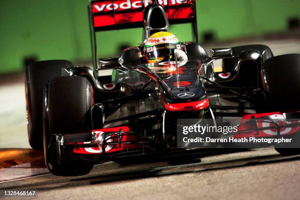 British McLaren Formula One racing driver Lewis Hamilton driving his MP4-26 racing car over chicane kerbs during practice for the 2011 Singapore...