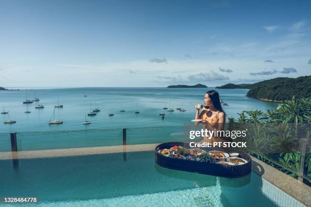 a woman drinking coffee and breakfast floating on the water beside the pool. - luxury hotel fotografías e imágenes de stock