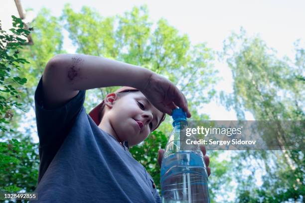 the boy opens a bottle of water - open workouts bildbanksfoton och bilder