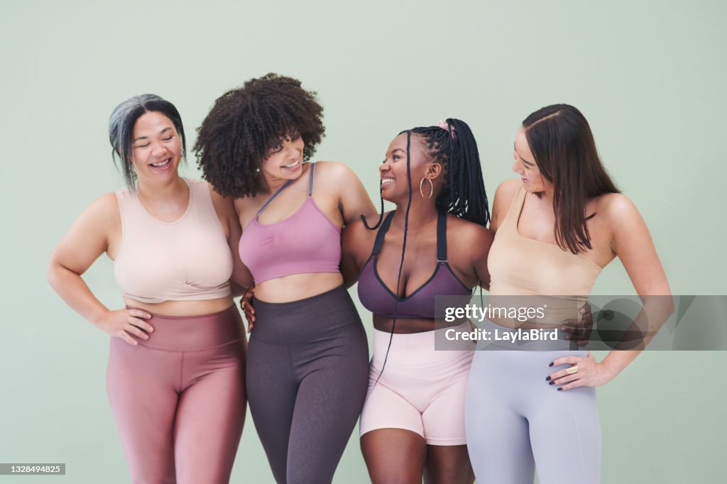 Studio shot of a group of women embracing each other against a green background