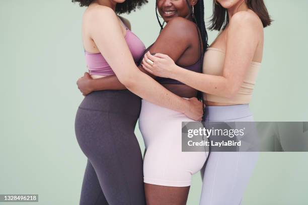 cropped studio shot of a group of unrecognizable women embracing each other against a green background - plus size fashion model stock pictures, royalty-free photos & images