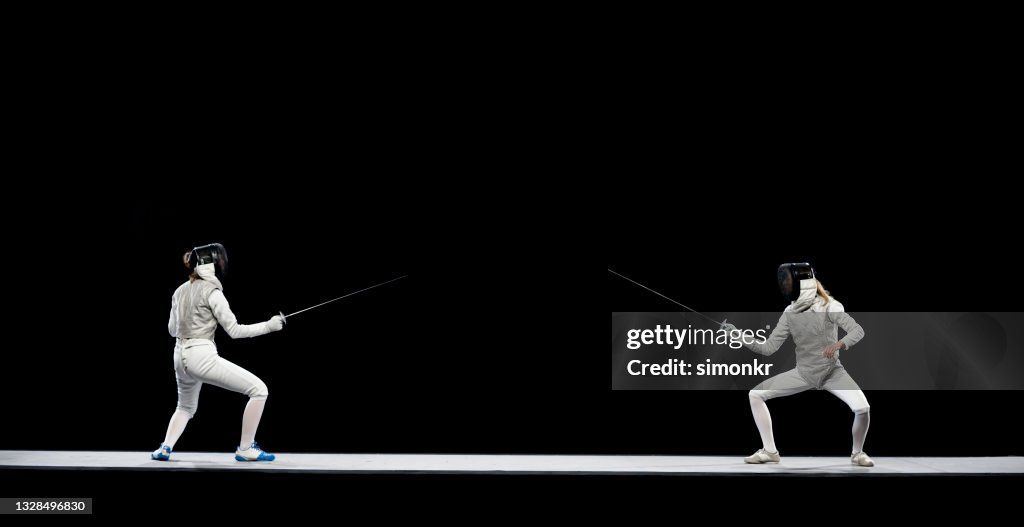 Female fencing athletes competing .