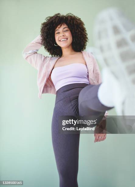 below shot of a young woman n a kicking pose against a green background - schoppen lichaamsbeweging stockfoto's en -beelden