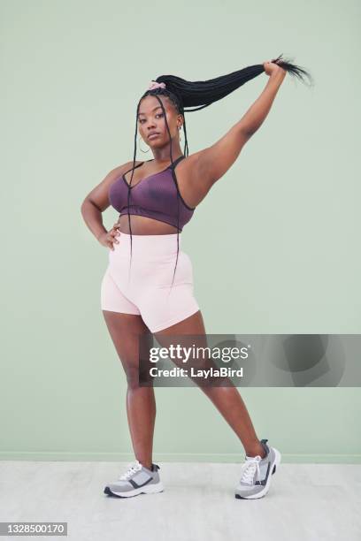 full body studio shot of a young woman pulling her hair and posing against a green background - female armpits stock pictures, royalty-free photos & images