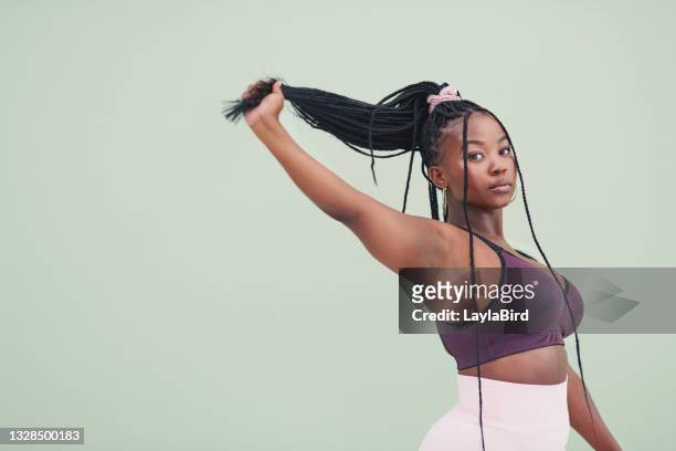 cropped studio portrait of a young woman pulling her hair and posing against a green background - sportswear stock pictures, royalty-free photos & images