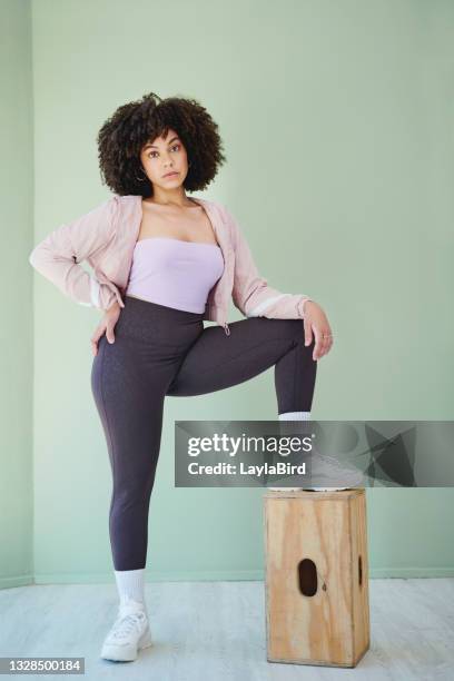 緑の背景に対して木製の構造に片足を持ち上げる若い女性の全身スタジオの肖像画 - female foot models ストックフォトと画像