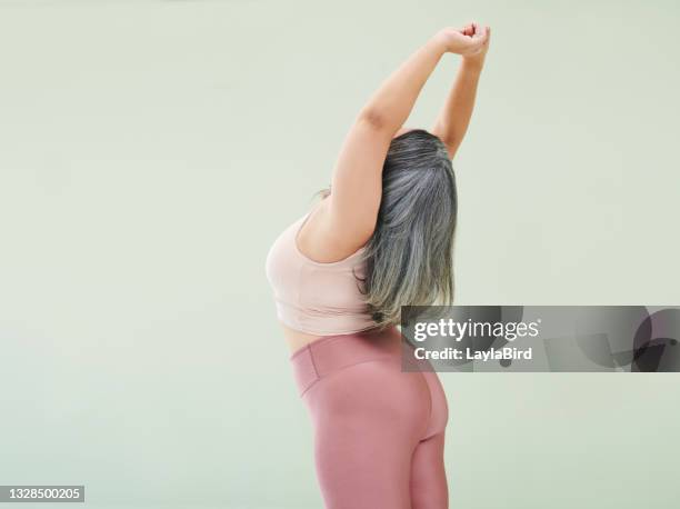 rear studio shot of an unrecognizable woman stretching against a green background - taking a shot - sport imagens e fotografias de stock