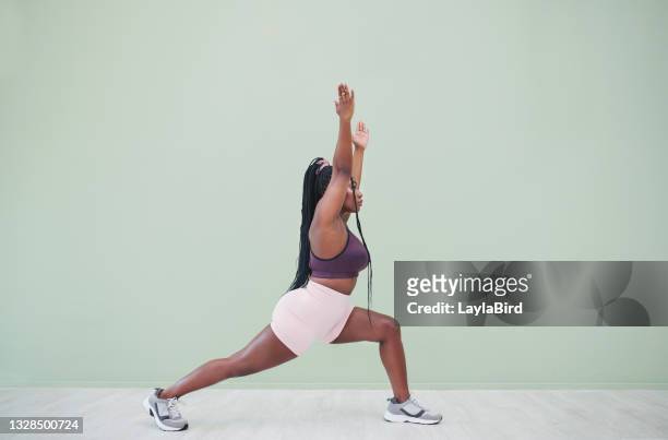 full body studio shot of a young woman exercising against a green background - human limb stock pictures, royalty-free photos & images