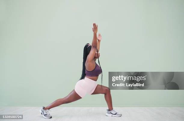 full body studio shot of a young woman exercising against a green background - lunge imagens e fotografias de stock