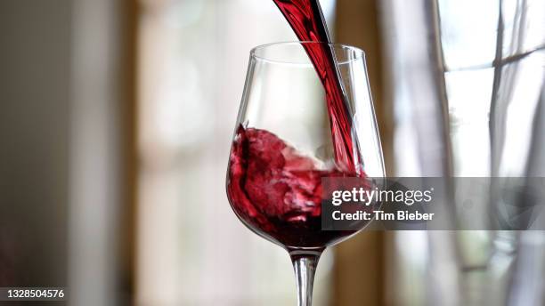 red wine being poured in to a wine glass. - maroon swirl stock pictures, royalty-free photos & images