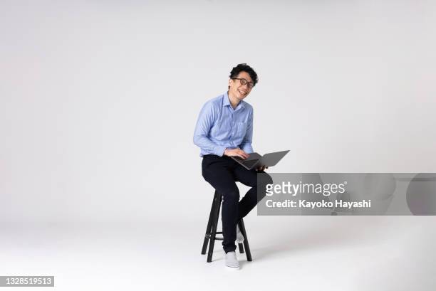 full-length portrait of an asian man on a white background. - stool imagens e fotografias de stock