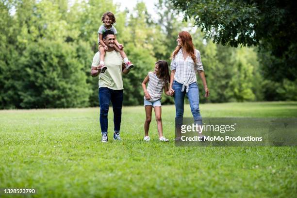family walking in the park - happy family grass stock-fotos und bilder