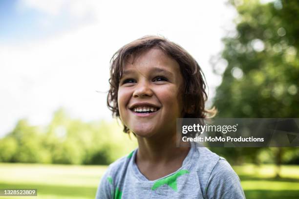 portrait of young boy smiling at park - menino a sonhar imagens e fotografias de stock