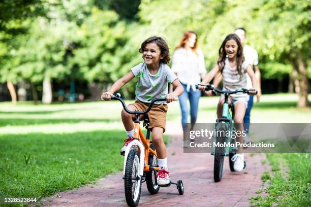 brother and sister riding bicycles in the park - activities park stock pictures, royalty-free photos & images