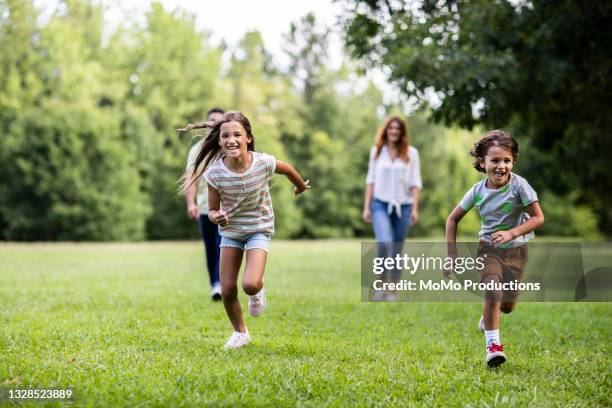 brother and sister running in the park - madre-corriendo fotografías e imágenes de stock