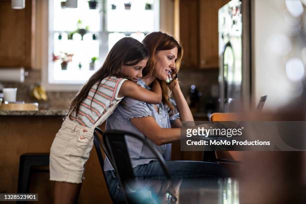 mother using laptop while daughter looks over her shoulder - women's short program imagens e fotografias de stock