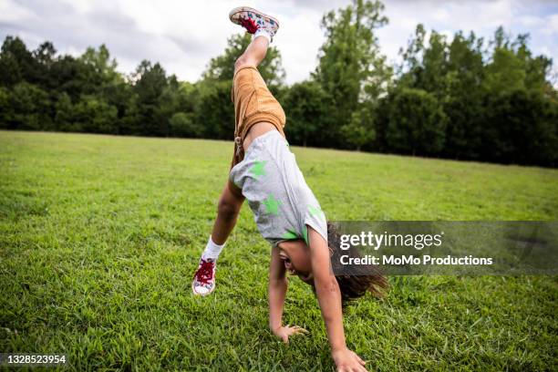 young boy doing a cartwheel at park - cartwheel gymnast stock pictures, royalty-free photos & images