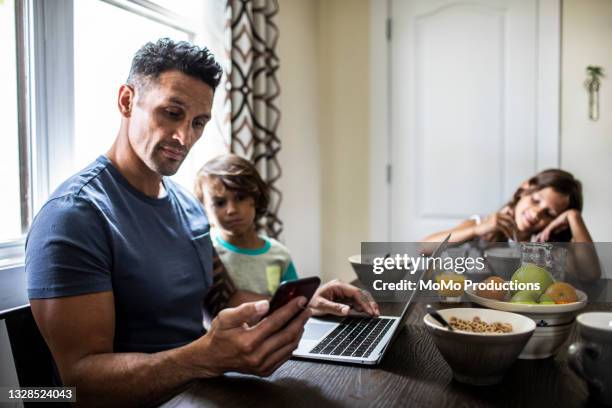 father using mobile device at breakfast with his children - child mobile phone stockfoto's en -beelden