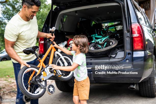 father and son loading bicycles into car - family road trip car stock pictures, royalty-free photos & images