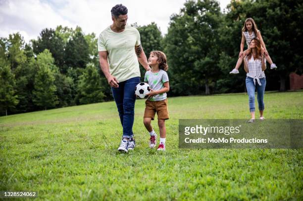 father and son walking in park with soccer ball - 8 ball stock-fotos und bilder