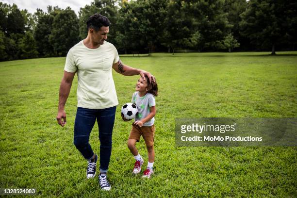 father and son walking in park with soccer ball - boys sport pants stock pictures, royalty-free photos & images