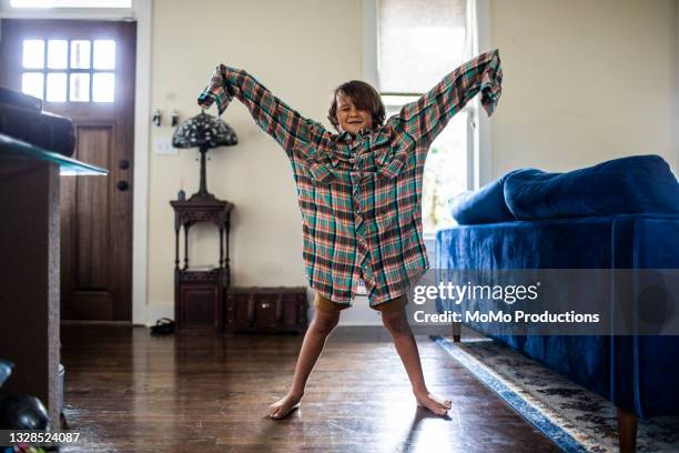 young boy wearing father's oversize shirt at home - passt nicht stock-fotos und bilder