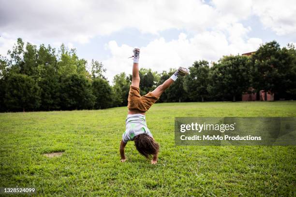 young boy doing a cartwheel at park - cartwheel stock pictures, royalty-free photos & images