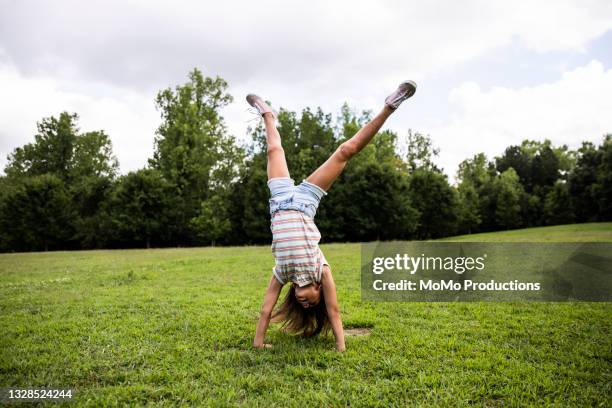 young girl doing a cartwheel at park - handstand fotografías e imágenes de stock