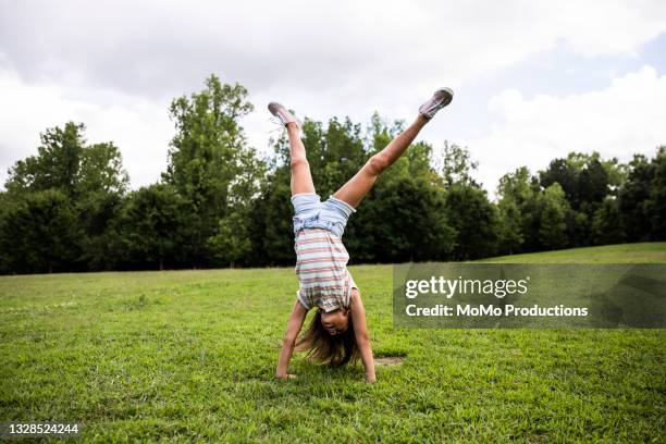 young girl doing a cartwheel at park - handstand - fotografias e filmes do acervo
