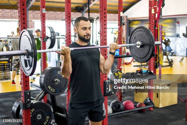 male athlete doing arm workout with barbell in gym - snatch stockfoto's en -beelden