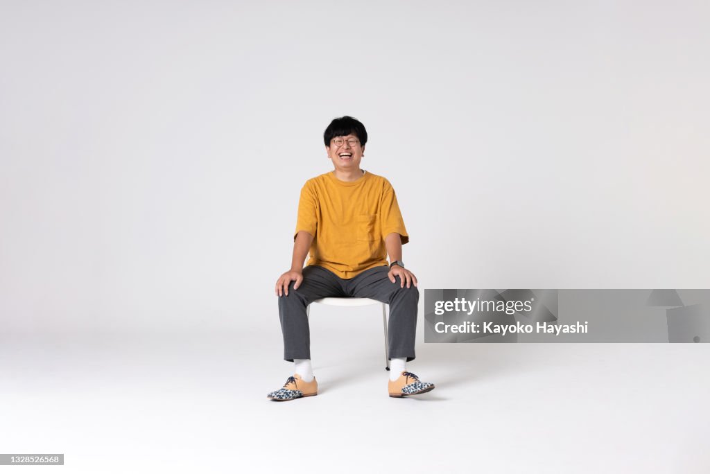 Full-length portrait of an Asian man on a white background.