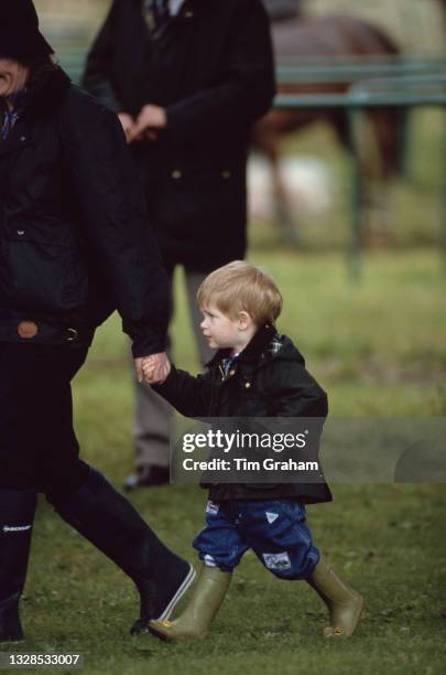 British Royal Prince Harry, wearing a waxed jacket, and wellington boots, having his hand held by Royal nanny Ruth Wallace Cirencester Park Polo Club...