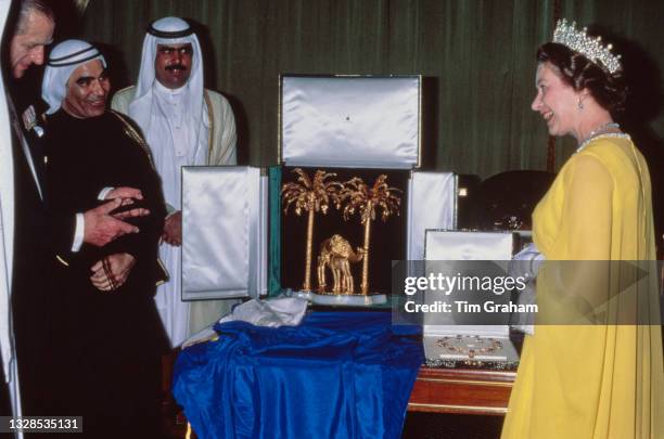 British Royal Queen Elizabeth II, wearing a yellow outfit with white gloves, and the Girls of Great Britain and Ireland Tiara, and Prince Philip,...