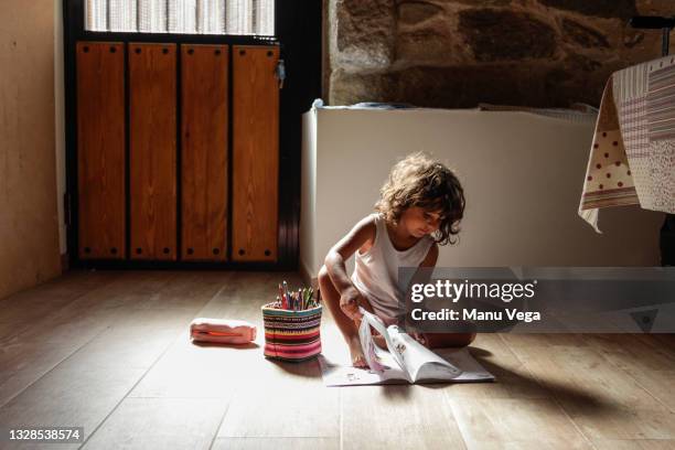 little girl sitting on the floor at home while drawing and coloring on a paper. - casa real española fotografías e imágenes de stock