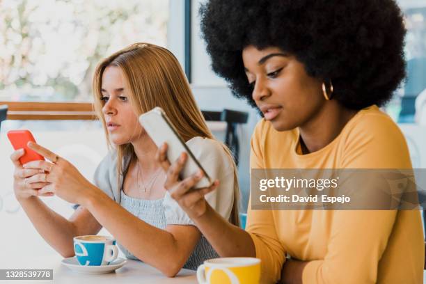 diverse girlfriends using cellphones in cafe - scrolling 個照片及圖片檔