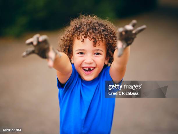 happy little boy playing in the mud - happy dirty child stockfoto's en -beelden