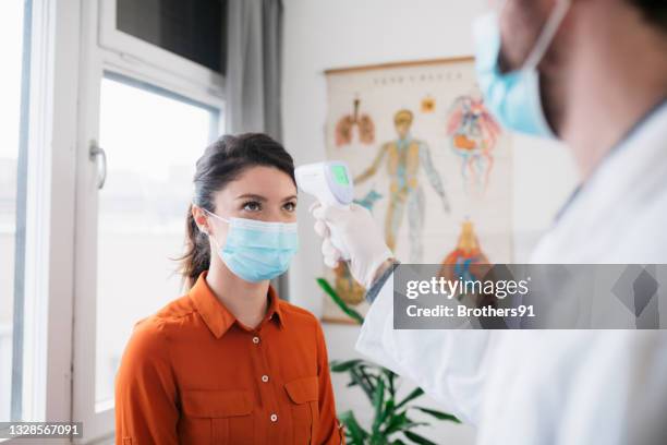 giovane donna caucasica controllata per la temperatura - misurare la temperatura foto e immagini stock